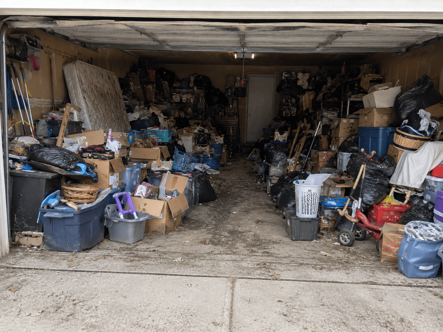Garage filled with boxes, bins, furniture, and household clutter before removal